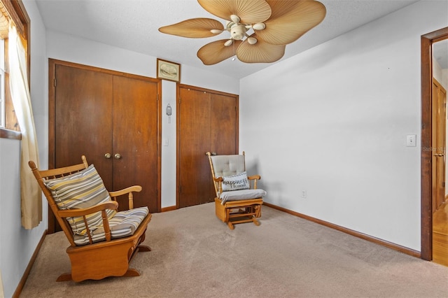 living area with baseboards, carpet, and a ceiling fan