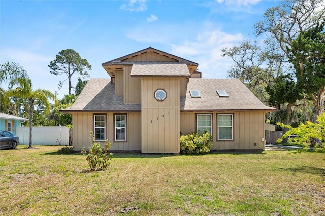 view of front of house with board and batten siding, fence, a shingled roof, and a front lawn