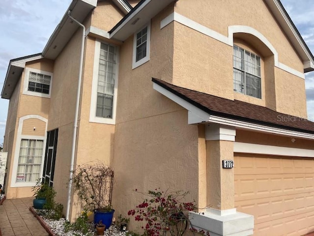 view of side of home featuring stucco siding and an attached garage