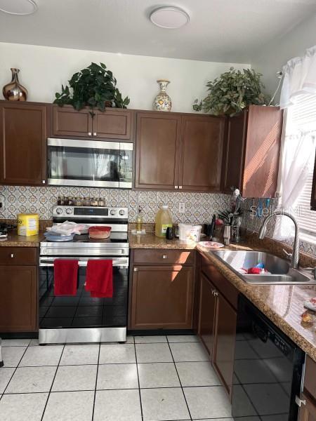 kitchen with light tile patterned floors, stainless steel appliances, decorative backsplash, and a sink