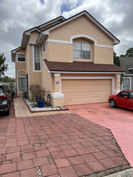 traditional home featuring an attached garage, stucco siding, and driveway