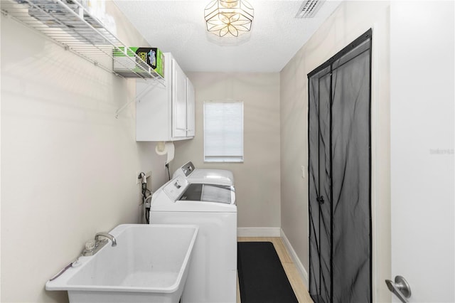 603 Yorkshire Dr, Oviedo, FL 32765 - clothes washing area with washing machine and dryer, cabinet space, baseboards, a textured ceiling, and light wood-type flooring