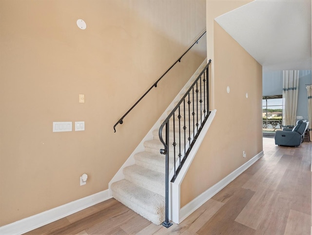 staircase with baseboards and wood finished floors