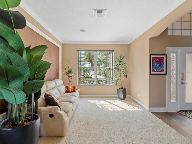 sitting room featuring baseboards, ornamental molding, visible vents, and wood finished floors