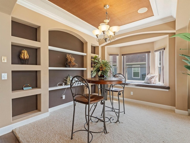 carpeted dining area with built in features, baseboards, ornamental molding, and a notable chandelier