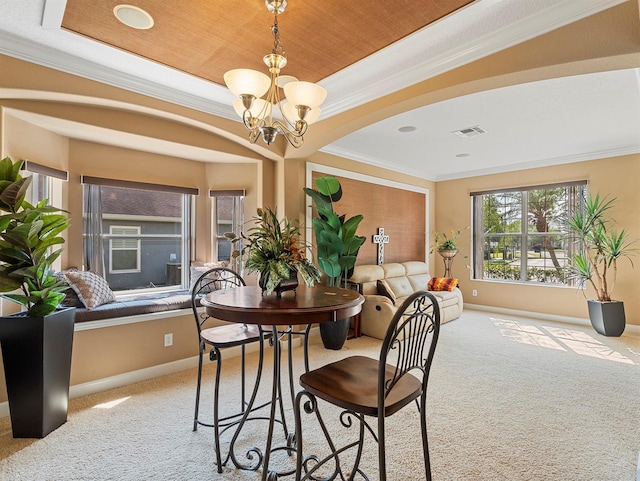 carpeted dining area with baseboards, ornamental molding, and an inviting chandelier