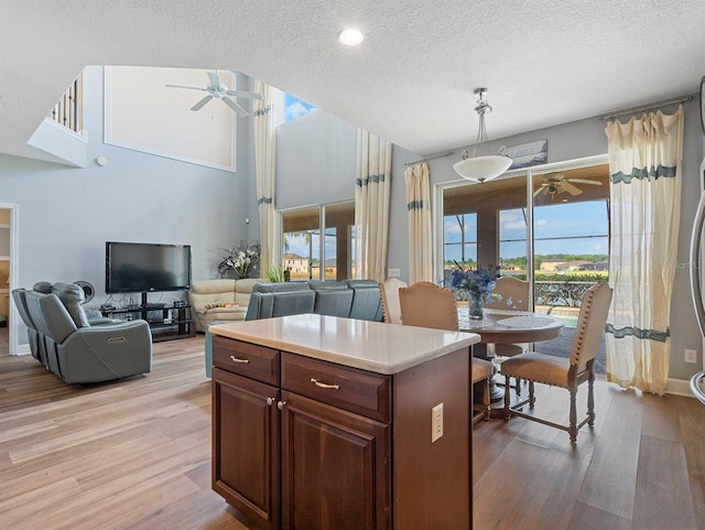 kitchen featuring a ceiling fan, pendant lighting, a textured ceiling, light wood-style floors, and light countertops