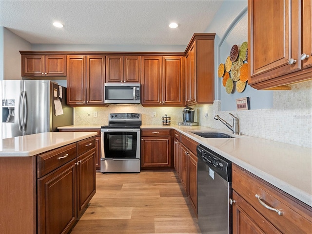 kitchen with a sink, stainless steel appliances, light countertops, decorative backsplash, and light wood-style floors