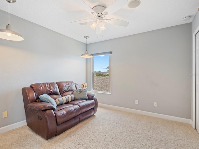 living area featuring light colored carpet, baseboards, and ceiling fan