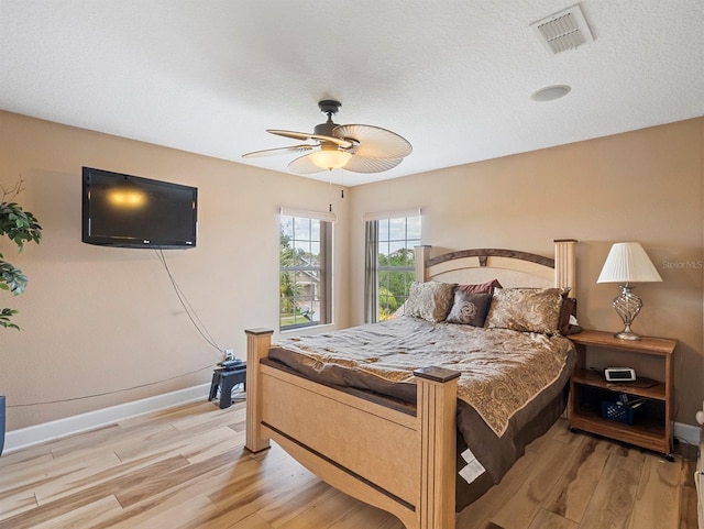 bedroom with light wood-style floors, visible vents, baseboards, and a ceiling fan