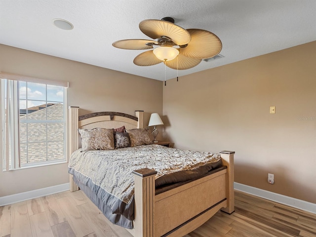 bedroom with baseboards, visible vents, and wood finished floors