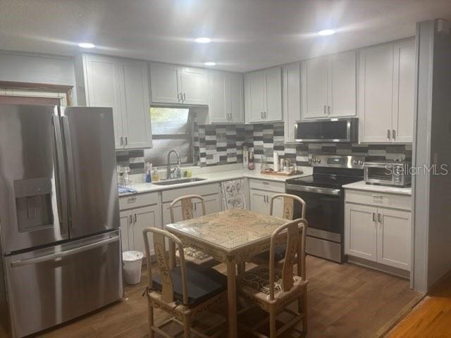404 E Kentucky Ave, Deland, FL 32724 - kitchen featuring stainless steel appliances, a sink, backsplash, light countertops, and wood finished floors