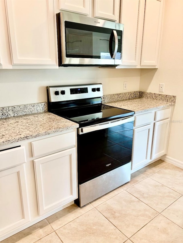 5216 Greenheart Ave, Mount Dora, FL 32757 - kitchen featuring appliances with stainless steel finishes, light stone counters, light tile patterned floors, and white cabinetry