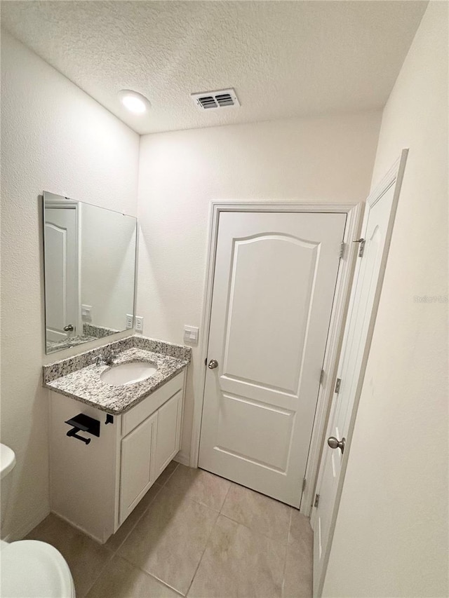 5216 Greenheart Ave, Mount Dora, FL 32757 - bathroom with a textured ceiling, toilet, visible vents, tile patterned flooring, and vanity