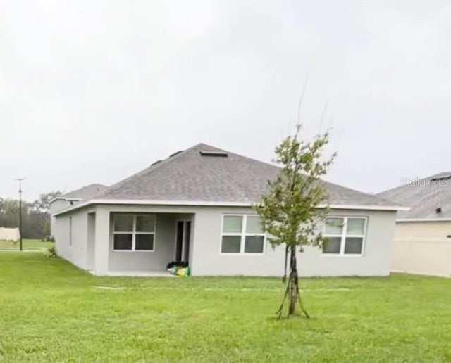 5216 Greenheart Ave, Mount Dora, FL 32757 - rear view of house featuring a yard, roof with shingles, and stucco siding