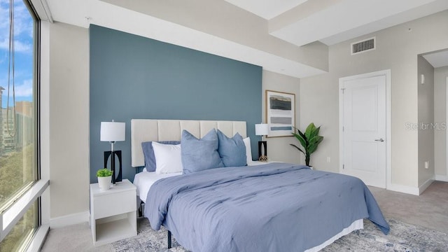 carpeted bedroom featuring visible vents, baseboards, and multiple windows