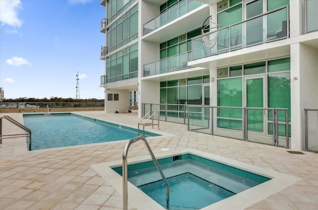pool with a hot tub and a patio area