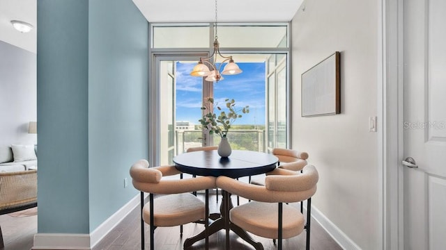 dining room featuring baseboards, a wealth of natural light, expansive windows, and wood finished floors