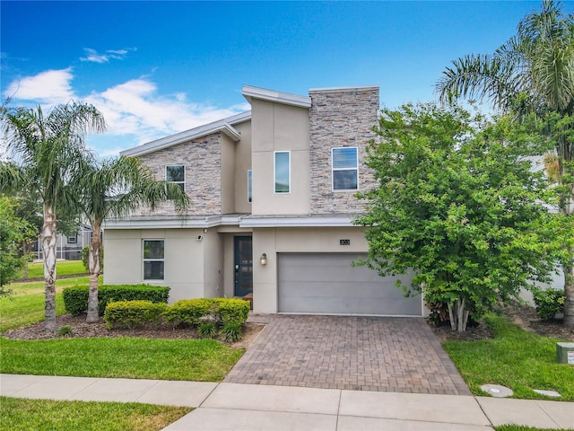 303 Ocean Course Ave, Davenport, FL 33896 - view of front of property with decorative driveway, a garage, stone siding, and stucco siding