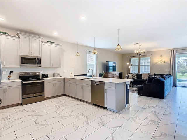 303 Ocean Course Ave, Davenport, FL 33896 - kitchen featuring appliances with stainless steel finishes, an inviting chandelier, gray cabinets, marble finish floor, and a peninsula