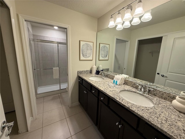 197 Jetty Way, Davenport, FL 33897 - bathroom with a shower stall, tile patterned flooring, double vanity, baseboards, and a textured ceiling