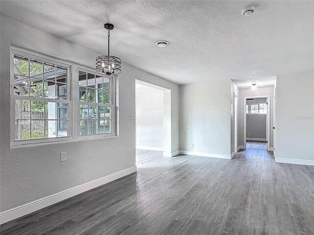 1298 Scottsdale Dr, Ormond Beach, FL 32174 - unfurnished living room with baseboards, a textured ceiling, an inviting chandelier, and wood finished floors
