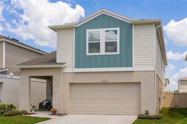 view of front facade with board and batten siding, fence, an attached garage, and driveway