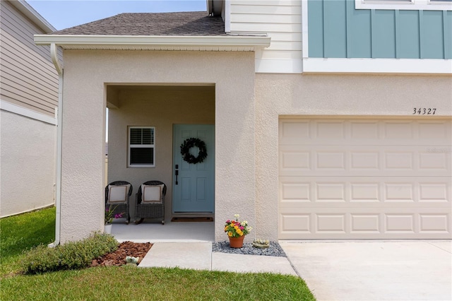 doorway to property featuring a shingled roof, stucco siding, and driveway