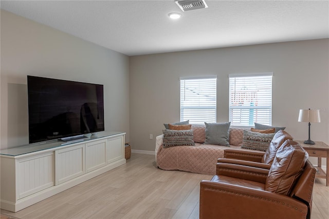 living area featuring baseboards, visible vents, and light wood finished floors