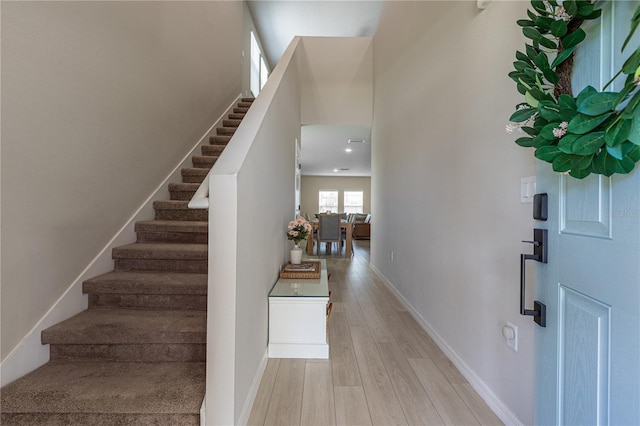entrance foyer with stairway, baseboards, and light wood-type flooring