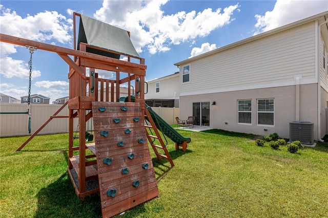 view of playground with a yard, central AC, and a fenced backyard