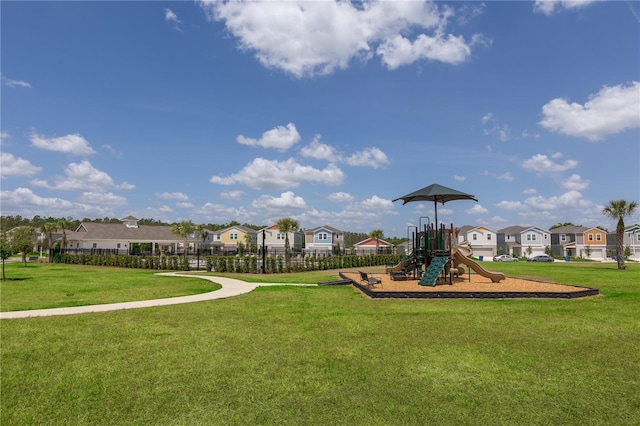communal playground with a lawn, fence, and a residential view