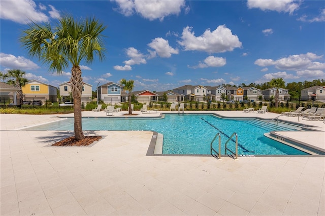 pool with a patio area, fence, and a residential view