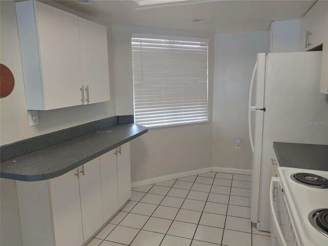 4109 Fairview Vista Pt Unit 315, Orlando, FL 32804 - kitchen featuring dark countertops, baseboards, white cabinetry, electric stove, and light tile patterned floors