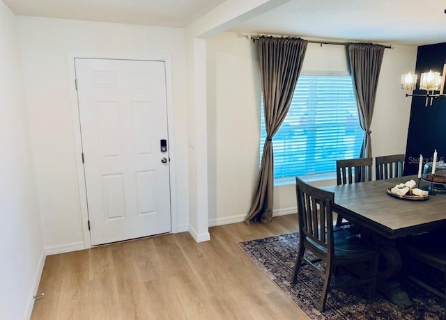 dining room with a chandelier, light wood-type flooring, and baseboards