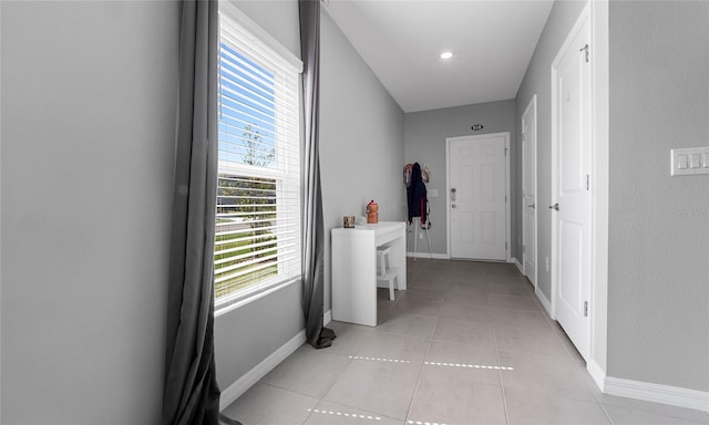 hall featuring baseboards, healthy amount of natural light, and light tile patterned floors