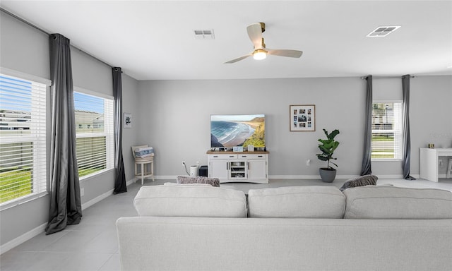 living room featuring a ceiling fan, baseboards, and light tile patterned floors