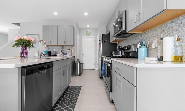 kitchen featuring appliances with stainless steel finishes, a sink, backsplash, light countertops, and recessed lighting