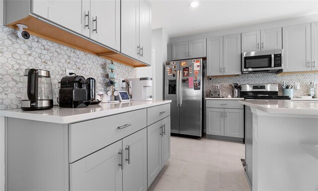 kitchen with appliances with stainless steel finishes, backsplash, light countertops, and gray cabinets