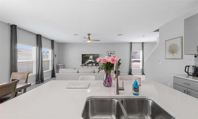 kitchen with a sink, light countertops, a ceiling fan, and open floor plan