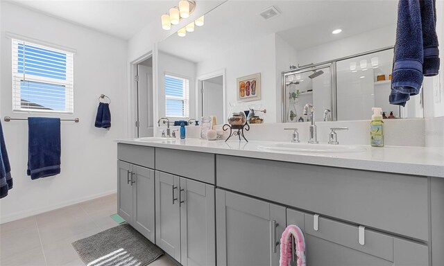 bathroom featuring healthy amount of natural light, a shower stall, double vanity, and tile patterned flooring