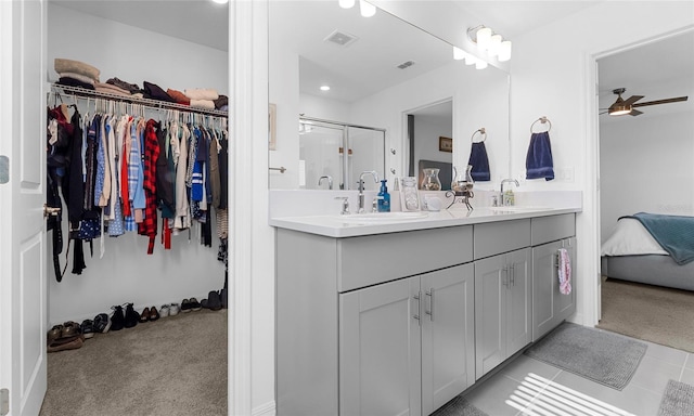 ensuite bathroom featuring double vanity, ceiling fan, a shower stall, a spacious closet, and tile patterned floors