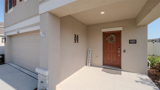 view of exterior entry featuring stucco siding and an attached garage