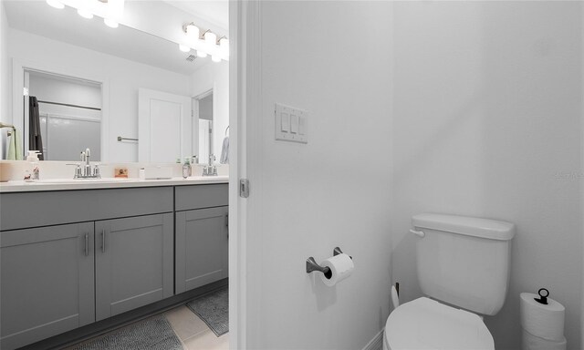 bathroom with toilet, vanity, and tile patterned flooring