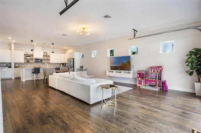living room with visible vents, recessed lighting, dark wood-type flooring, and a garage