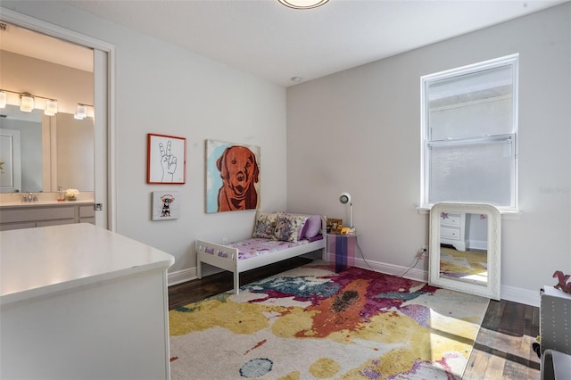 bedroom with a sink, baseboards, ensuite bathroom, and wood finished floors