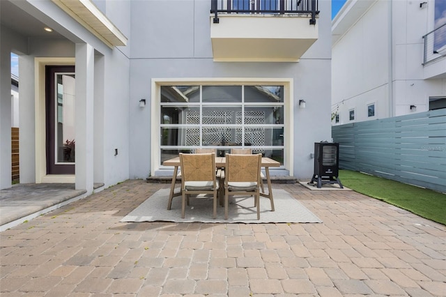 view of patio with fence, outdoor dining area, and a balcony
