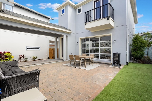 rear view of house featuring a patio, stucco siding, a yard, and a balcony