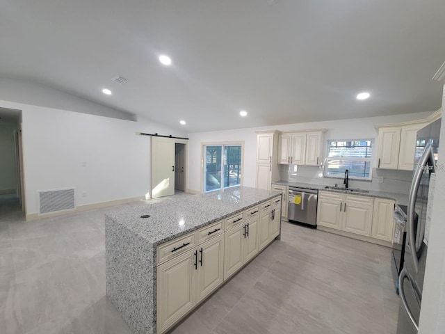 kitchen with a kitchen island, visible vents, a barn door, a sink, and stainless steel appliances