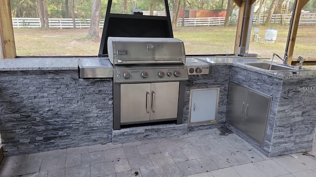 view of patio / terrace featuring fence, a sink, grilling area, and exterior kitchen